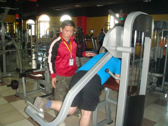 09级学生胡春雨在博雄健身教练部实习，正在给会员指点动作
